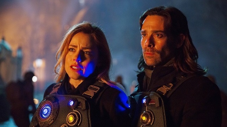 Cassie Railly (Amanda Schull) and Athan Cole (James Callis) stand together wearing futuristic outfits in 12 Monkeys