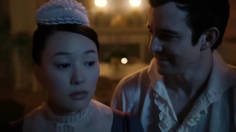  Luke Thompson and Yerin Ha looking at each other in Bridgerton. 