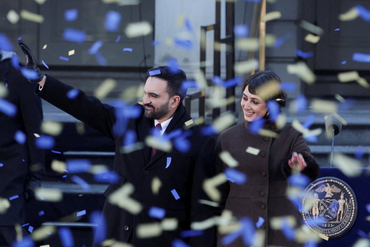 Two people wave as confetti drops.