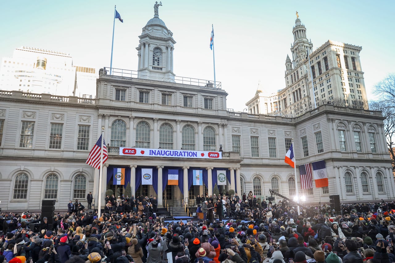 A large audience around an outdoor stage watch a swearing-in ceremony.