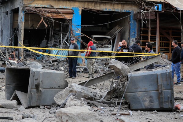 People check the site where an Israeli strike destroyed a building at a commercial district in the southern port city of Sidon, Lebanon, Tuesday, Jan. 6, 2026. (AP Photo/Mohammed Zaatari)