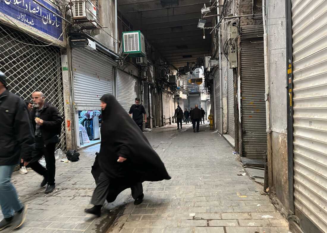 People walk as shops are closed during protests in Tehran's centuries-old main bazaar, Iran, Tuesday, Jan. 6, 2026.