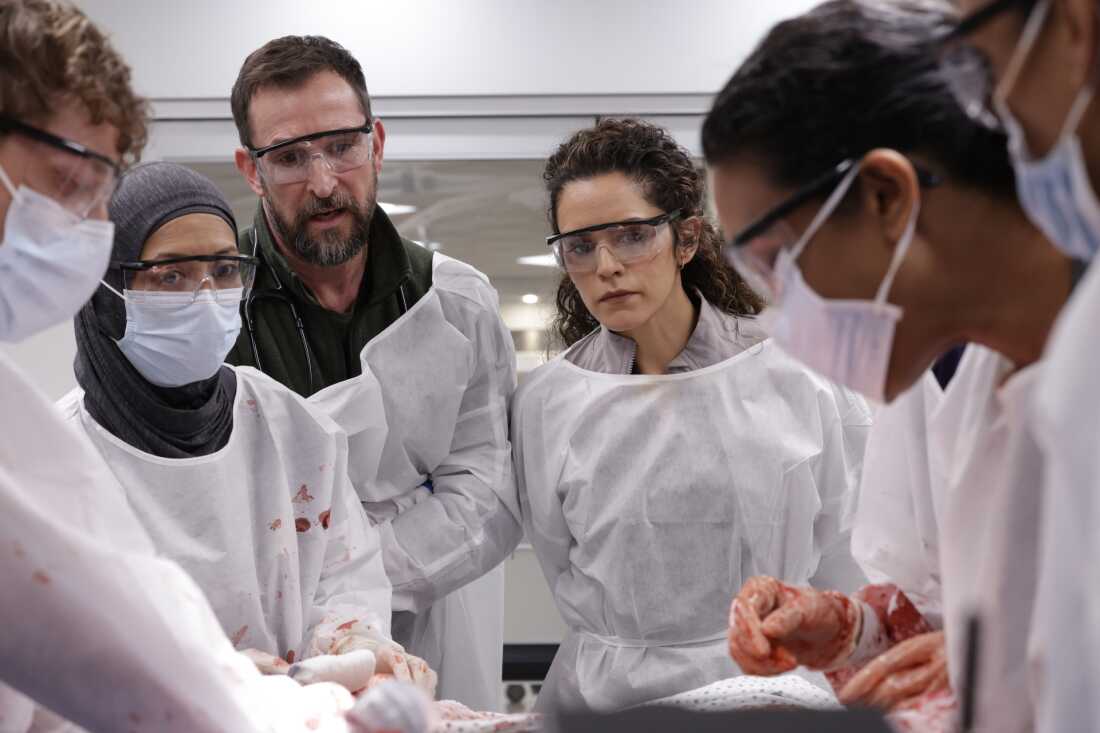 Sepideh Moafi, fourth from left, as Dr. Baran Al-Hashimi, the new attending physician, huddles with her team around a patient in a fictional Pittsburgh teaching hospital in the HBO Max series The Pitt.