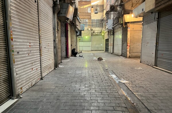 FILE - A man sits as shops are closed during protests in Tehran's centuries-old main bazaar, Iran, Jan. 6, 2026. (AP Photo/Vahid Salemi)