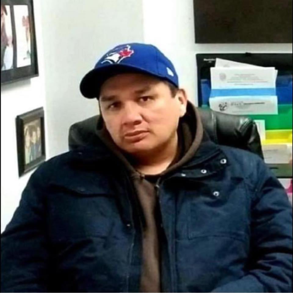 A man wearing a coat and Blue Jays baseball cap.