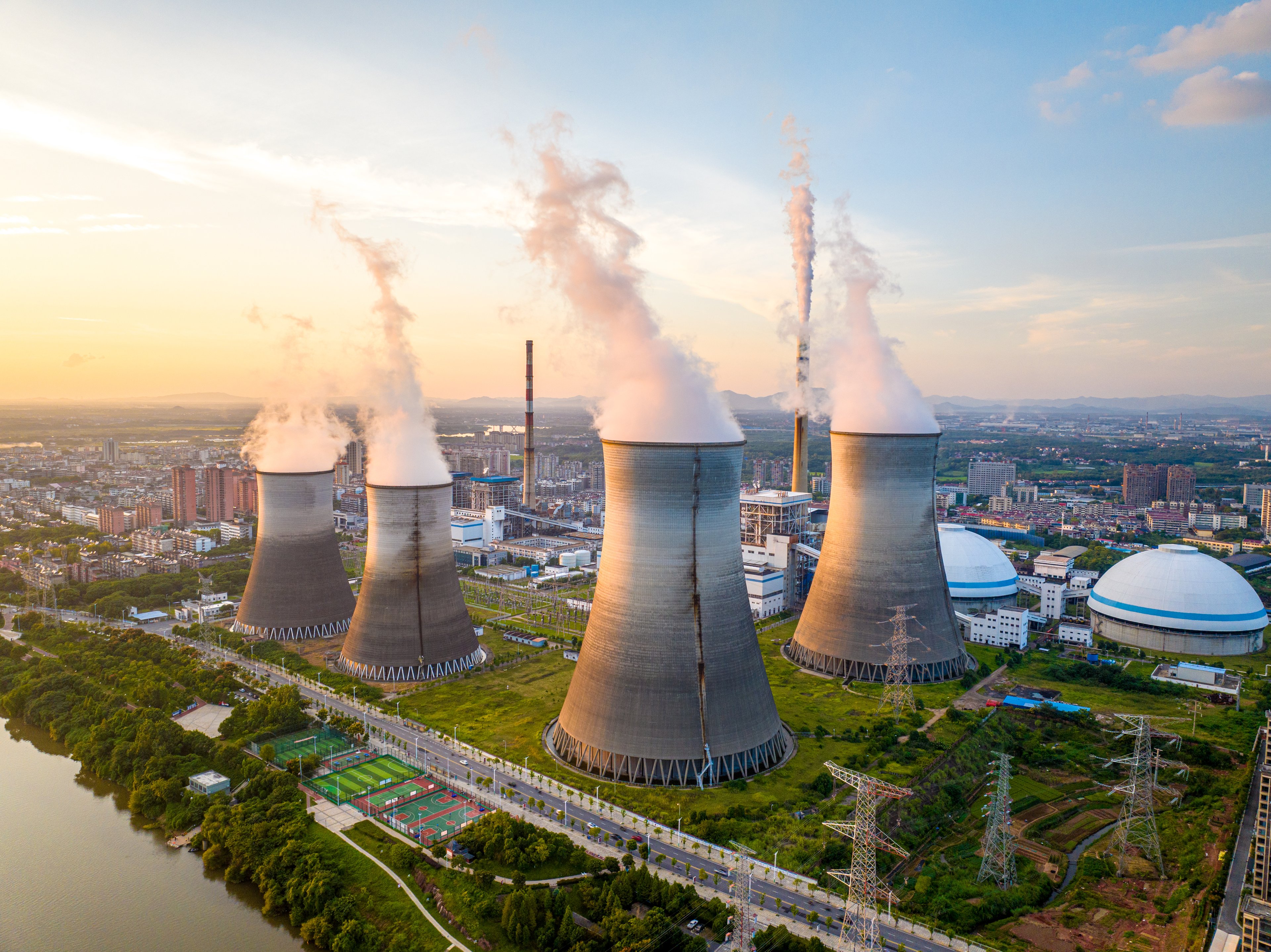 Aerial view of a nuclear power plant with four cooling towers steaming.
