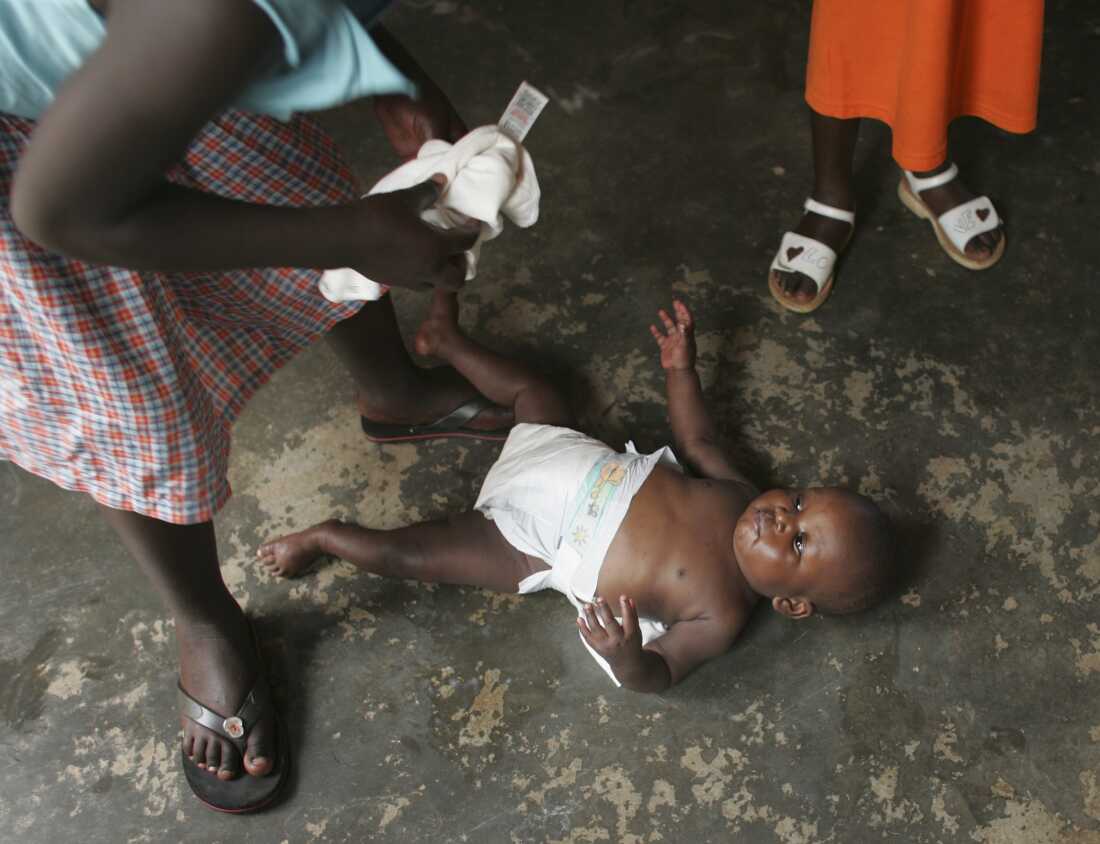 MPIGI, UGANDA - DECEMBER 6: A nurse changes 18 month year old Joel, an HIV positive orphan on the floor of the Aidchild Orphanage on December 6, 2005 in Mpigi, 60 km north of the capital Kampala, Uganda. Aidchild provides homes, academics and clinics for about 70 orphans living with AIDS who do not have the support of extended families. Uganda is pioneering the battle against AIDS in Sub-Saharan Africa, bringing its national prevalence of the disease down from a peak of 18.3% to an estimated 6.2% currently.