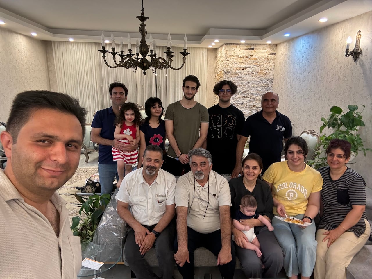 A photo of an extended family sitting on a living room couch together.