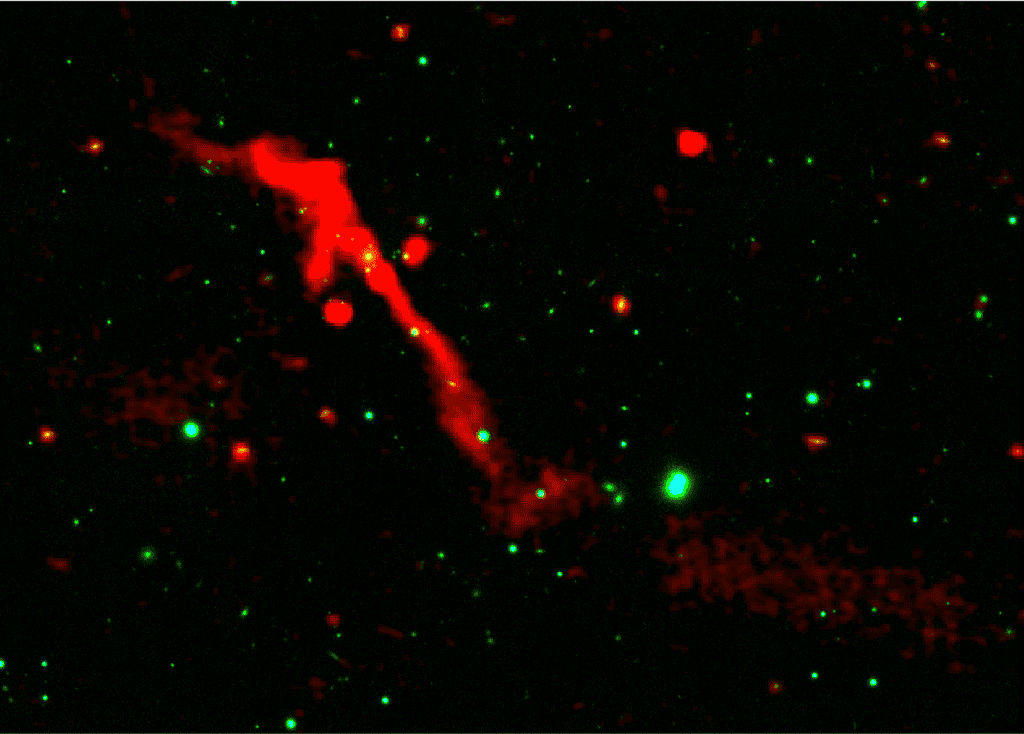 Giant red streak (black hole jet ejection) in space with green stars. Radio image of galaxy 