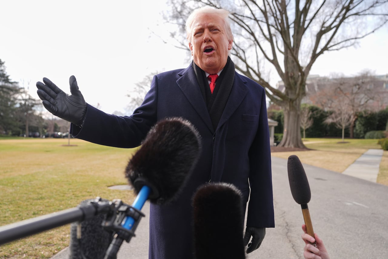 A man speaks at a microphone, standing outside