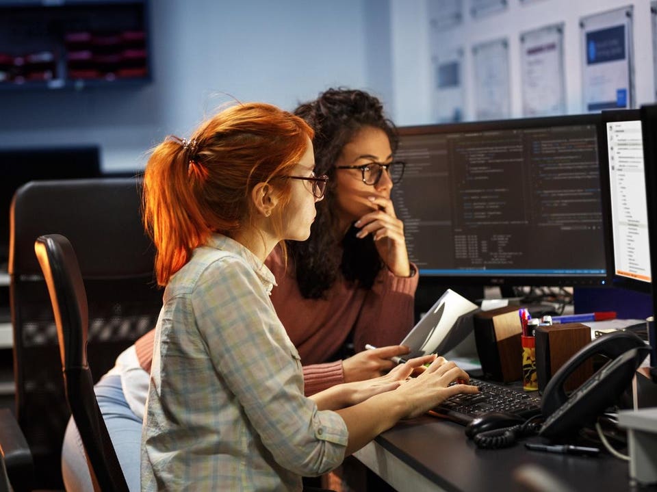 Two female programmers working on new project.They working late at night at the office.