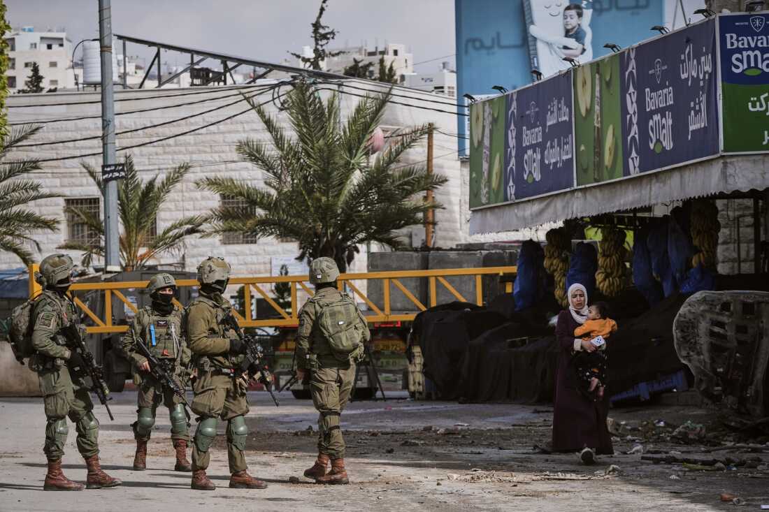 Israeli soldiers take up positions during an army raid in the West Bank city of Hebron Monday, Jan. 19, 2026.