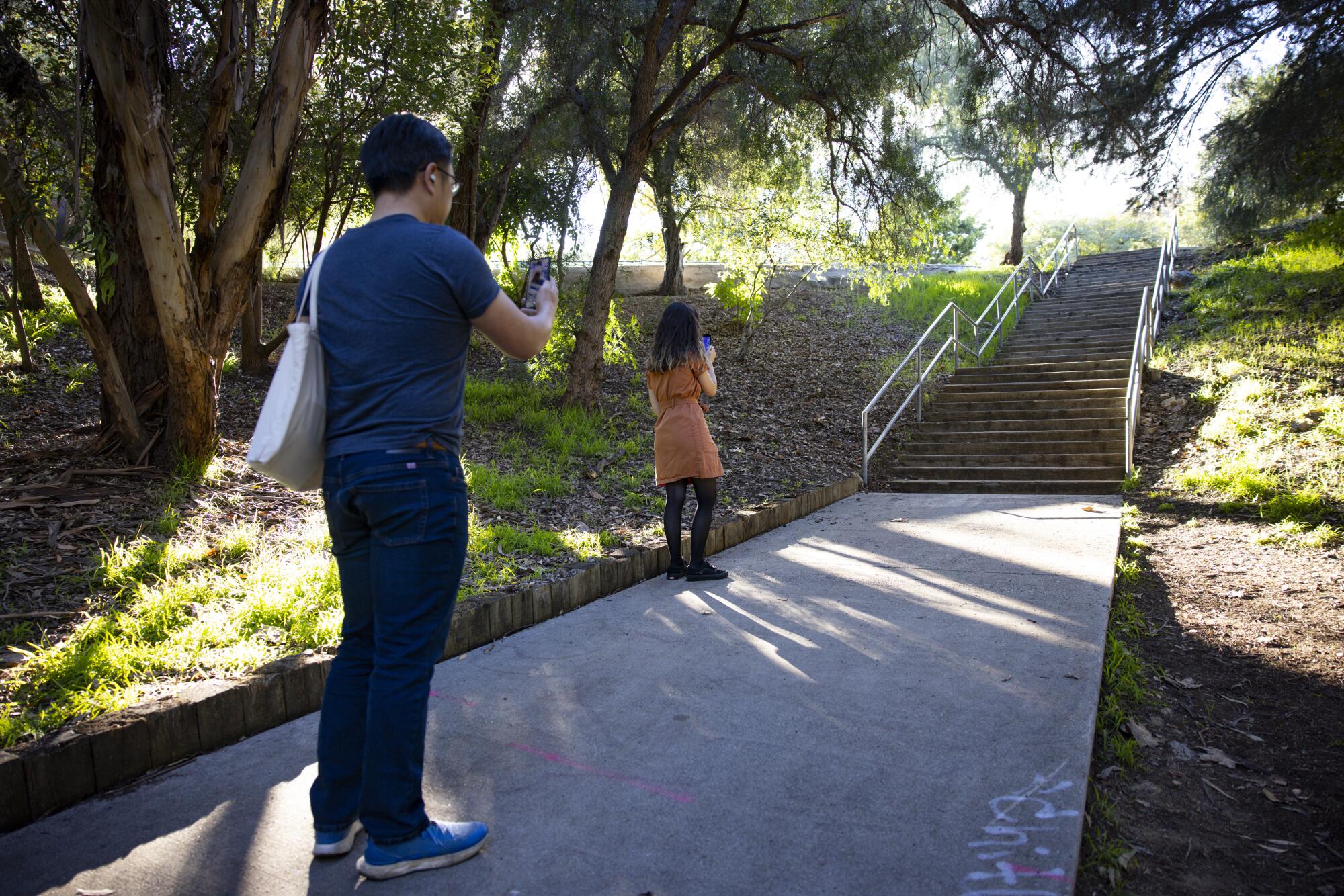 Two people on phones look at a staircase.