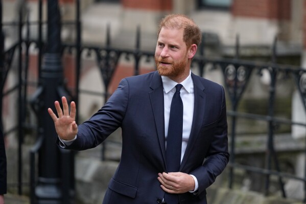 Britain's Prince Harry waves as he arrives at London's High Court to lead a group, including Elton John and Elizabeth Hurley, accusing the Daily Mail's publisher of privacy invasion through unlawful tactics in a trial that is part of a wider phone hacking scandal in London, Monday, Jan. 19, 2026. (AP Photo/Alastair Grant)