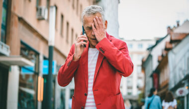 Low angle front view close-up of Caucasian man in early 60s learning bad news as he pauses to take an outdoor call during city break in Ljubljana.