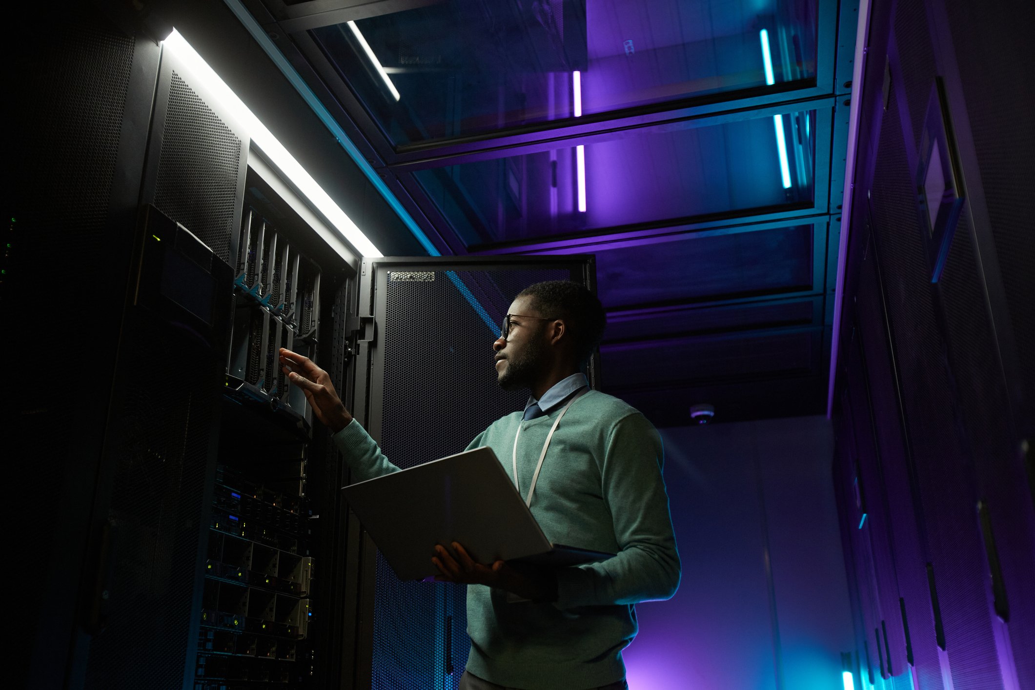 Engineer in a data center looking at computing hardware.
