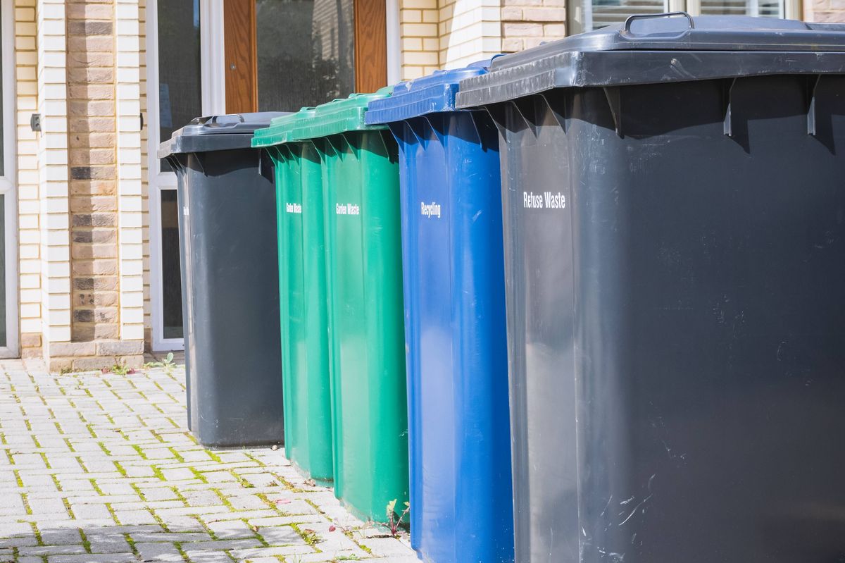 Wheelie bins outside the front doors, labelled for recycling, garden waste and refuse waste at the Grahame Park Estate in London