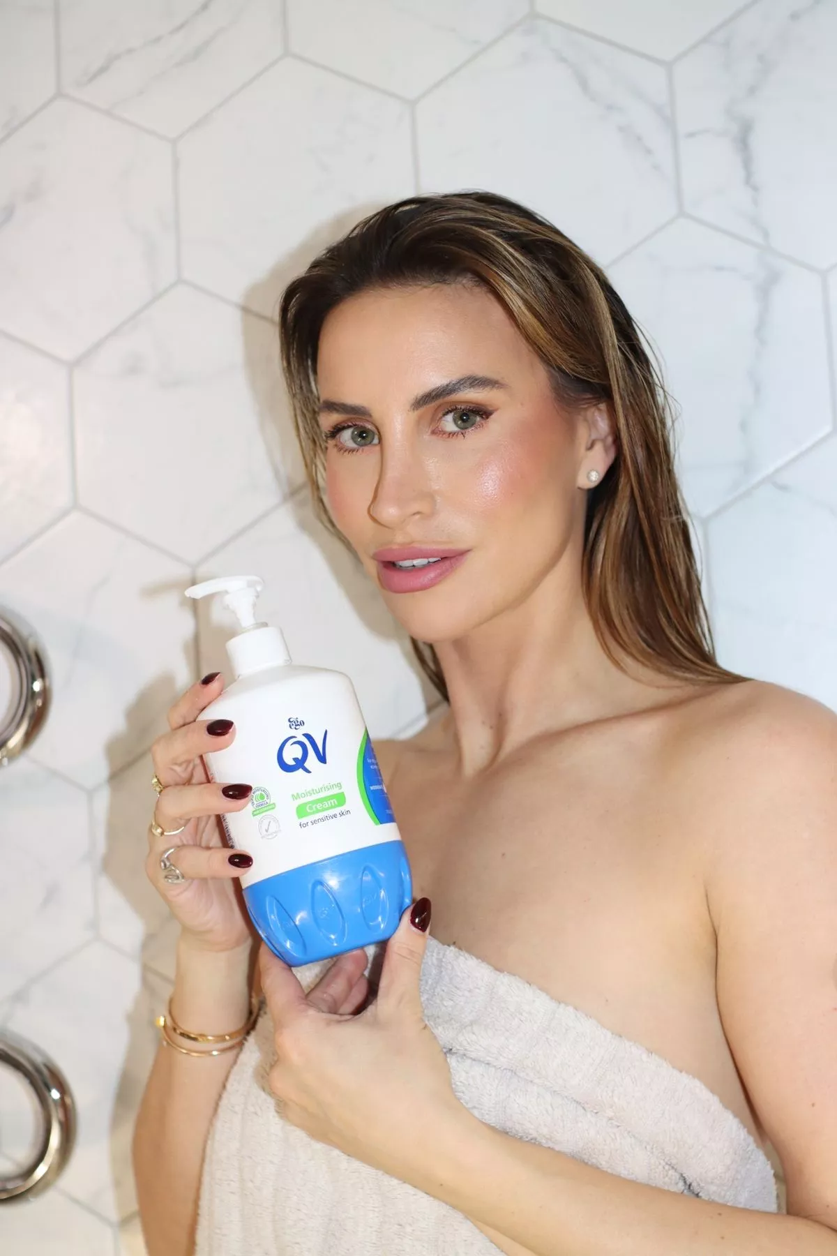 ferne mccann holding bottle of qv moisturiser