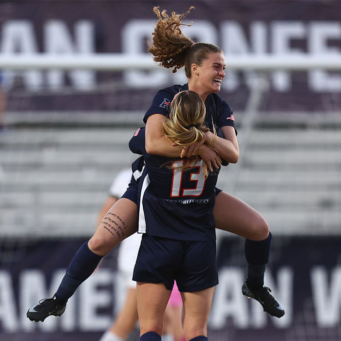 A women's soccer player jumps into the arms of her teammate