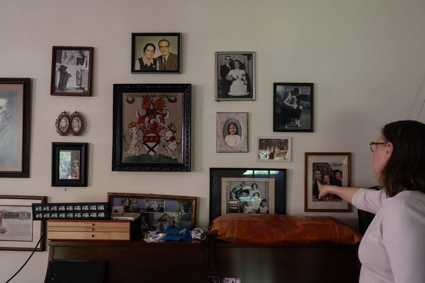 A woman pointing at a wall with pictures.