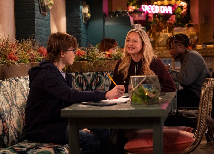 26_01_coro_sam_beth_01 Megan sits down beside Sam, who is doing his homework in Speed Daal, in a scene from Coronation Street