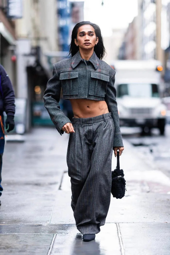 Bretman Rock in stylish, cropped blazer and loose-fitting pants walks confidently on the city street, carrying a small handbag