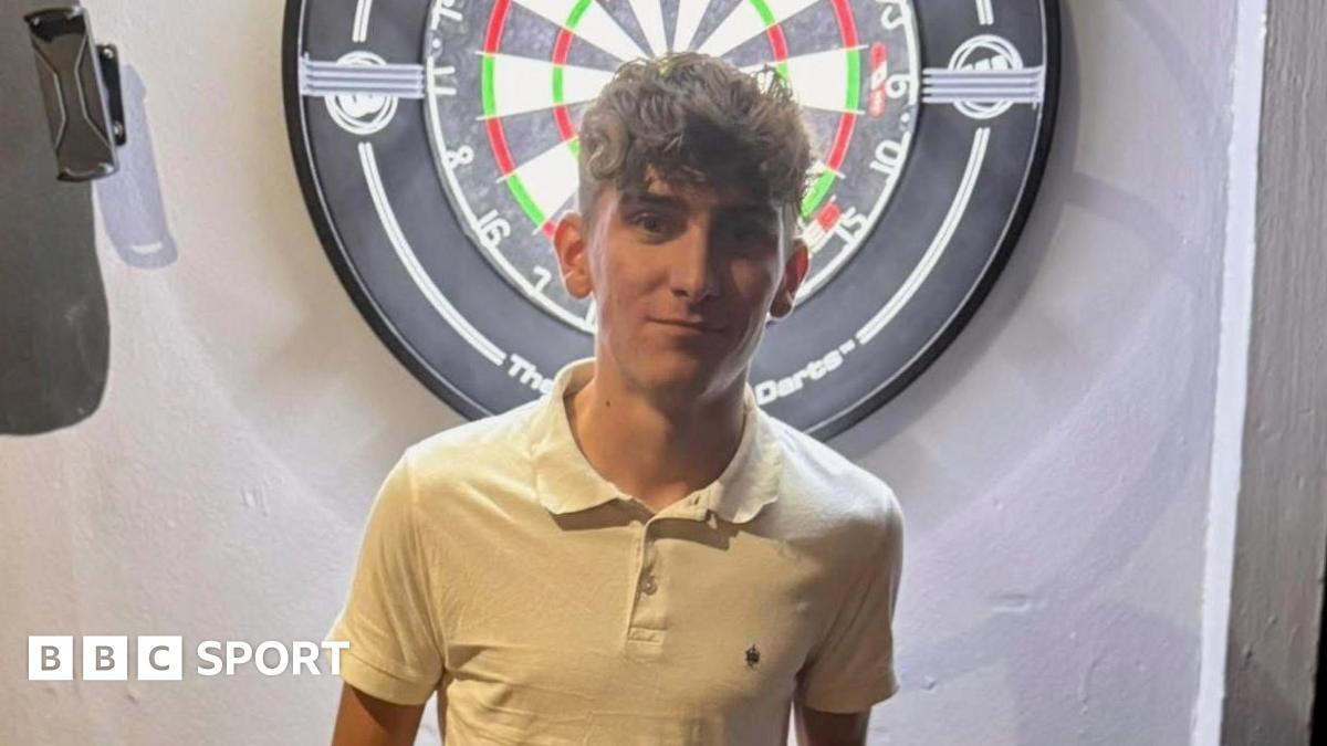 Tyler Thorpe poses in front of a dartboard