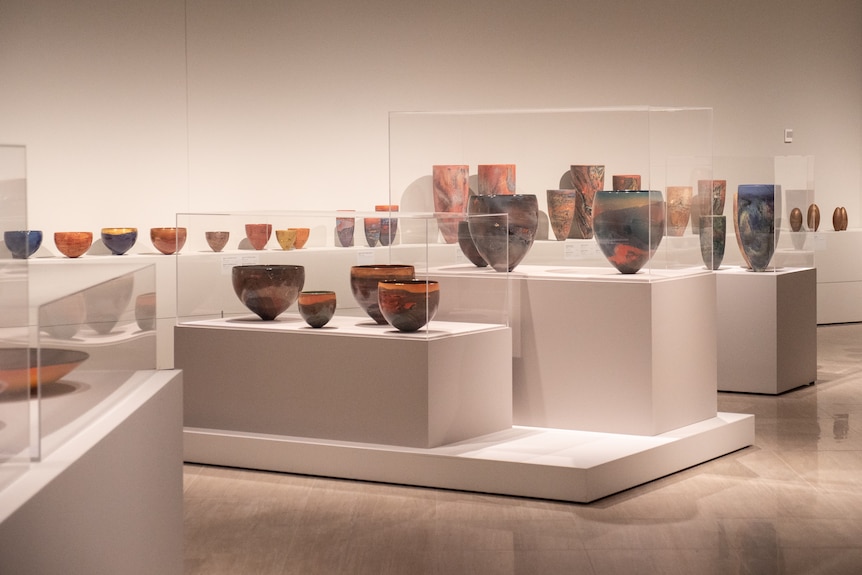 Clusters of colourful porcelain pieces on display in art gallery space
