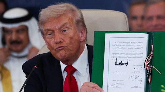 Donald Trump holds a signed document during a summit to support ending the war in Gaza. 