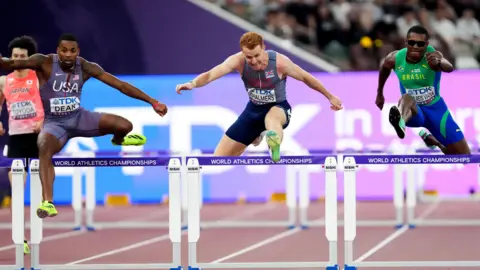 Martin Rickett/PA Wire Image shows Alastair Chalmers smiling, in a grey zipped jumper and white T-shirt. He is pictured at the Foote's Lane training ground, with the track and trees featured behind him, on a cold, cloudy winter's day.