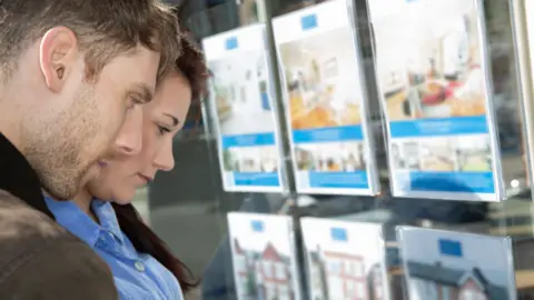 Getty Images Young couple look at houses for sale in an estate agent's window