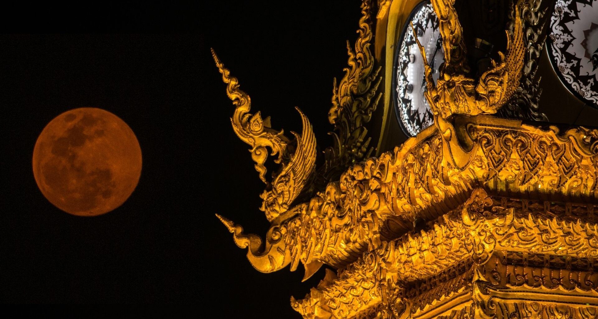Photo of a red moon and the golden clock tower of Chiang Rai province the northern part of Thailand.
