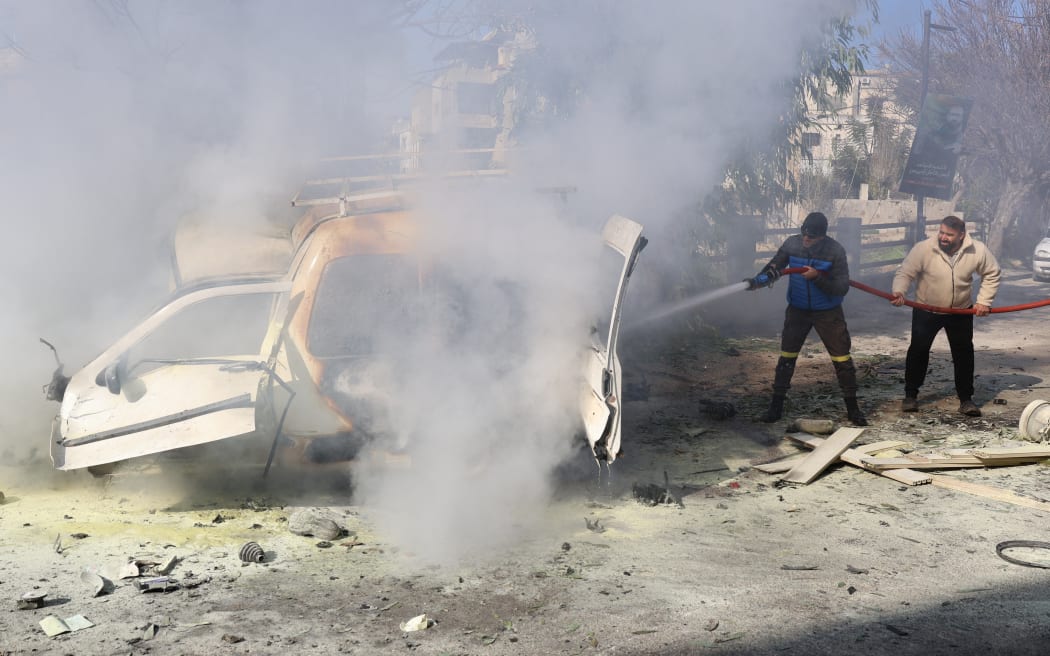 A firefighter and a civilian extinguish fire from a car following an Israeli strike in the southern Lebanese village of Khiam on January 3, 2026.