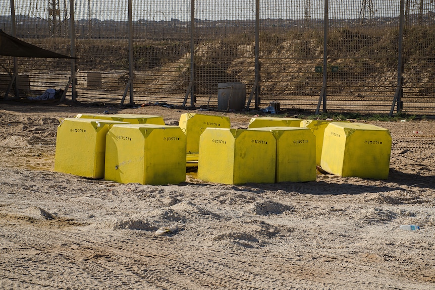 Several large concrete blocks in front of fencing