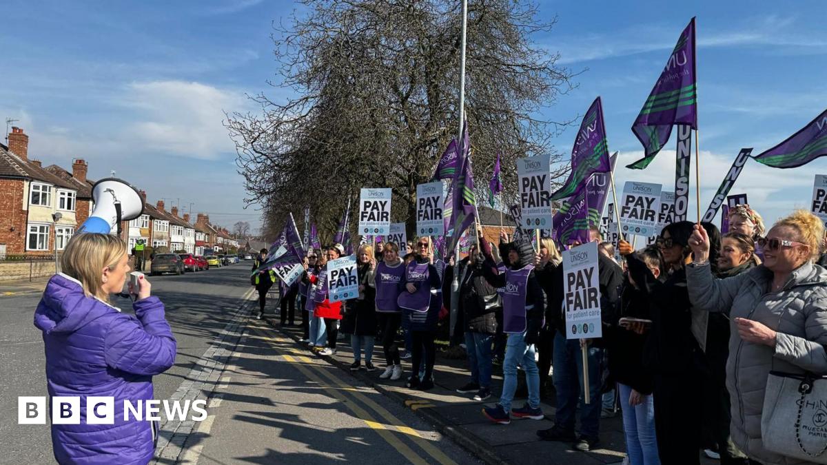 Donald Trump and Keir Starmer sit in a formal drawing room setting  on arm chairs with US and UK  flags behind them. Both have serious expressions and are looking out and not at each other.