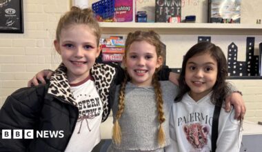 Three girls with their hair braided smiling at the camera.