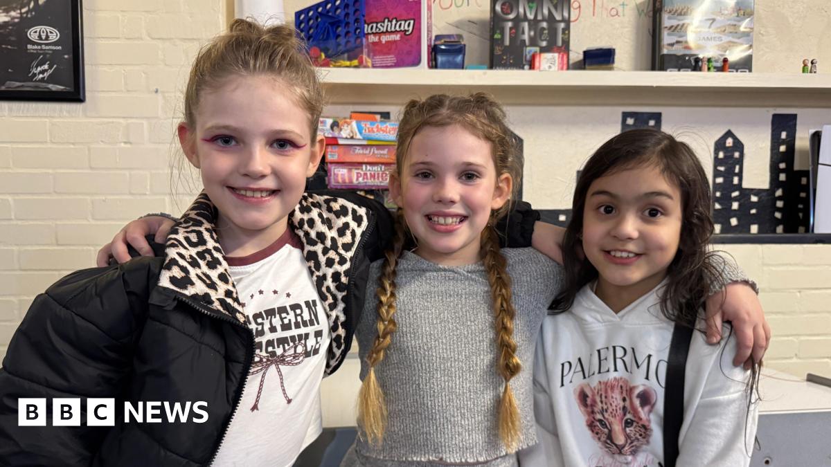 Three girls with their hair braided smiling at the camera.