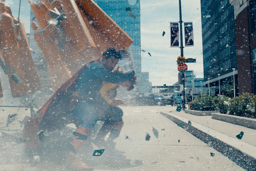 Superman saving a small girl from an explosion on the street