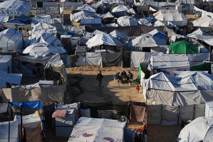 Displaced Palestinians gather outside a tent at a temporary camp in Deir al-Balah, central Gaza Strip, Saturday, Jan. 17, 2026. (AP Photo/Abdel Kareem Hana)