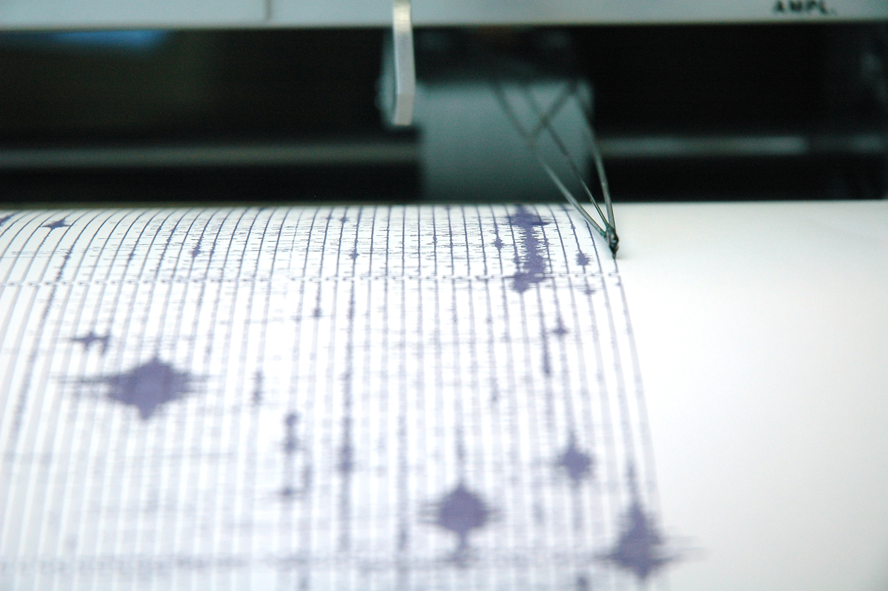 A needle on a seismograph records earthquake data. On the left are the needle lines showing seismic activity.