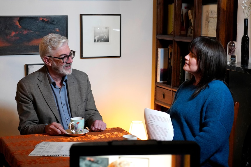 A man and a woman sit at a desk with papers on it