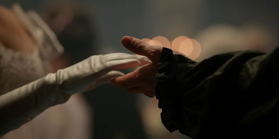 Sophie Baek's gloved hand reaches for Benedict Bridgerton's. (Netflix)