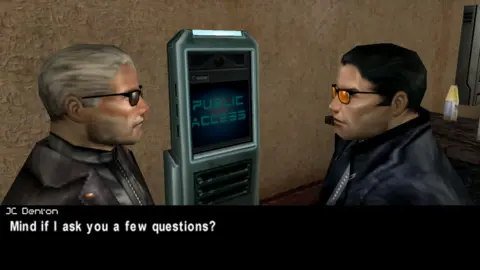 Eidos A screenshot from the video game Deus Ex. Two men in the game are staring at each other, in front of a machine with the words "Public Access" written on it. The dislogue at the bottom reads "JC Denton: Mind if I ask you a few questions?".