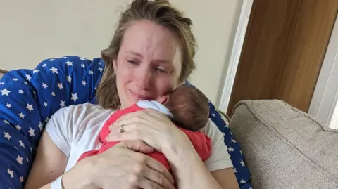 Louise cuddles her newborn baby, while she is crying