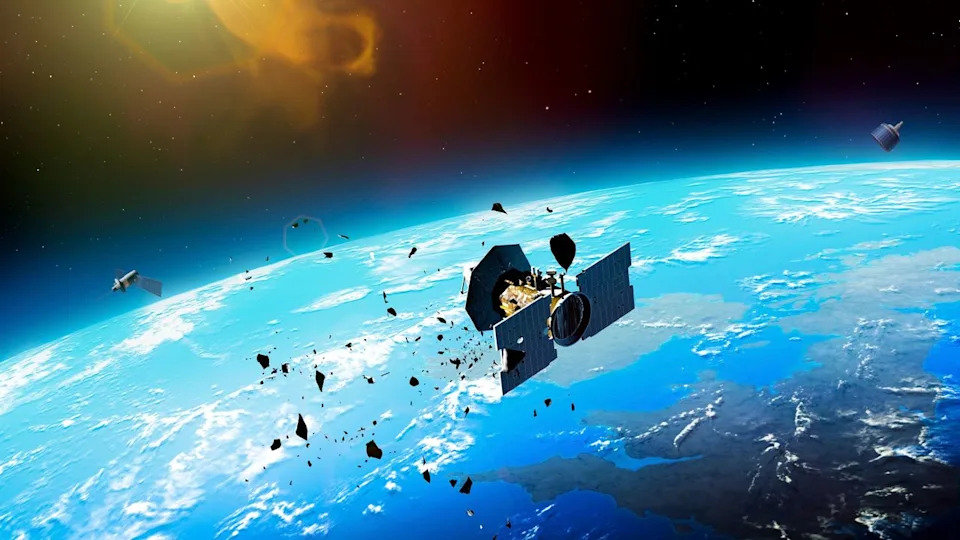 An illustration of a cylindrical satellite breaking apart into multiple pieces above earth.