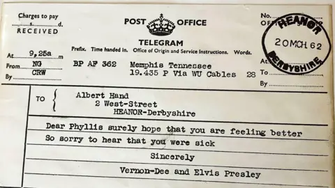 A telegram with reads the sent address as Memphis Tennessee. The postal mark reads Heanor, Derbyshire sent on the 20th March 1962. The message reads 'Dear Phyllis surely hope that you are feeling better So sorry to hear that you were sick Sincerely Vernon-Dee and Elvis Presley'