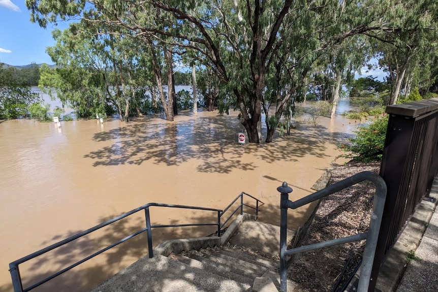 A carpark covered in brown water, with it lapping at the bottom of a strong staircase 