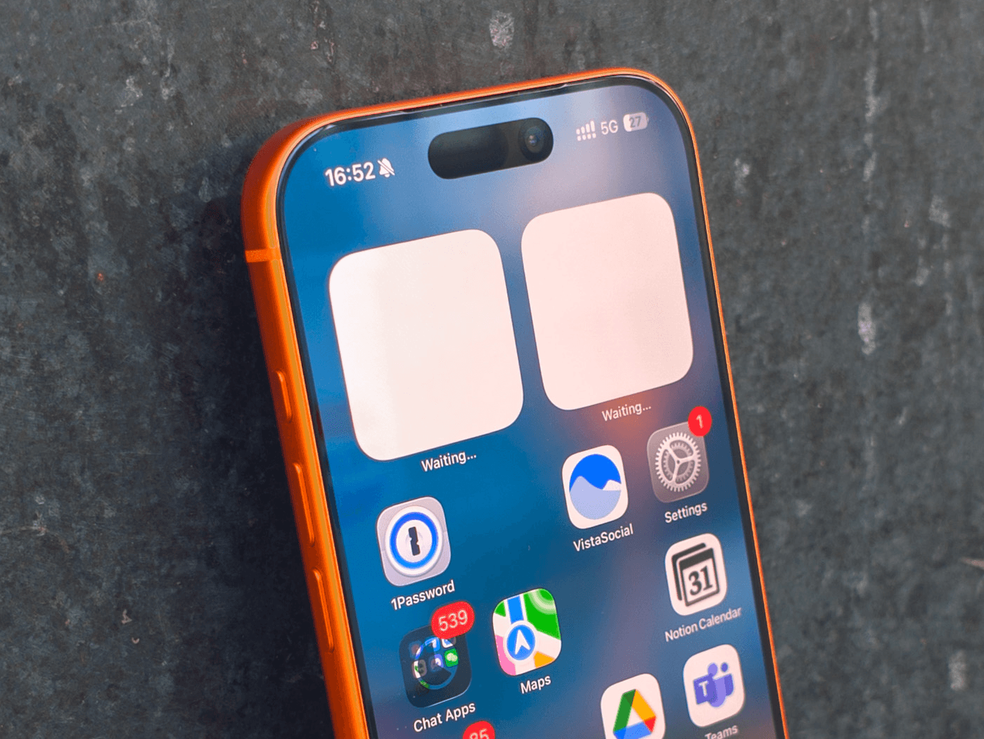 Apple iPhone 17 Pro in Cosmic Orange leaning on a gray wall.