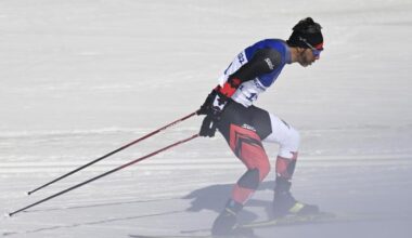A side view of a male cross-country skier going though a haze of snow during a race.