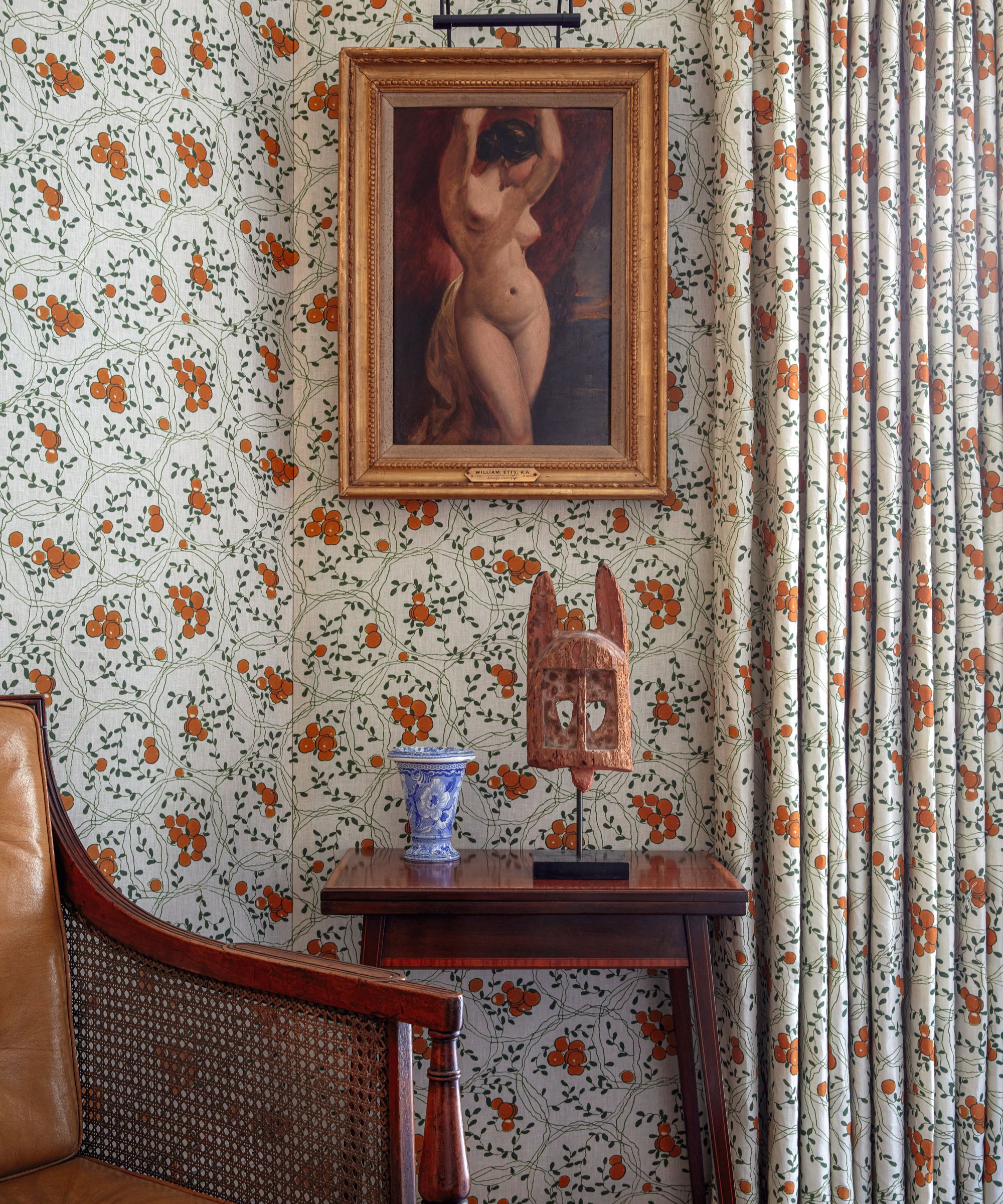 a sitting area with patterned wallpaper that matches the drapes, a small table, and artwork on the wall